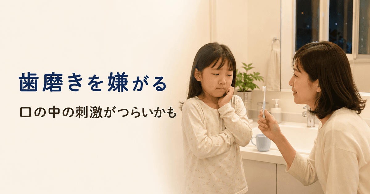 洗面所で、歯磨きへの不安から口を閉じて頬へ手を当てる小学生と、子どもの目線に近い位置で歯ブラシを見せながら穏やかに話す保護者。「歯磨きを嫌がる 口の中の刺激がつらいかも」と表示されている画像。